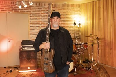 Un bassiste de Heartline portant une casquette pose avec sa basse dans un studio d’enregistrement.