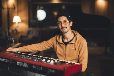 Un claviériste d’Os Pariocas pose devant son clavier rouge au studio Midilive.