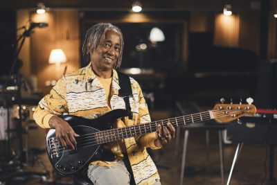 Un bassiste d’Os Pariocas pose avec sa basse électrique au studio Midilive.