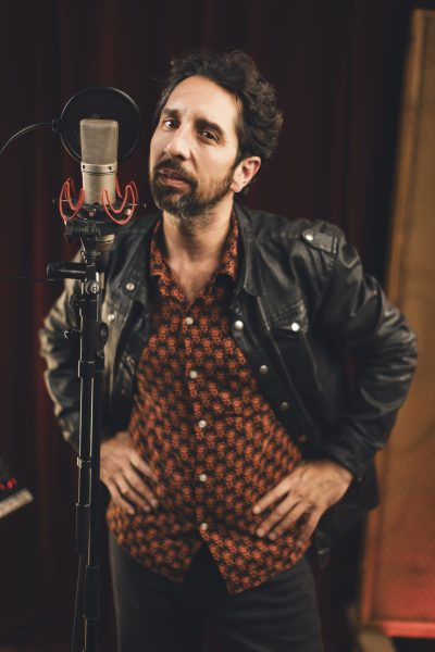 Portrait d’un membre d’Os Pariocas debout devant un microphone au studio Midilive.